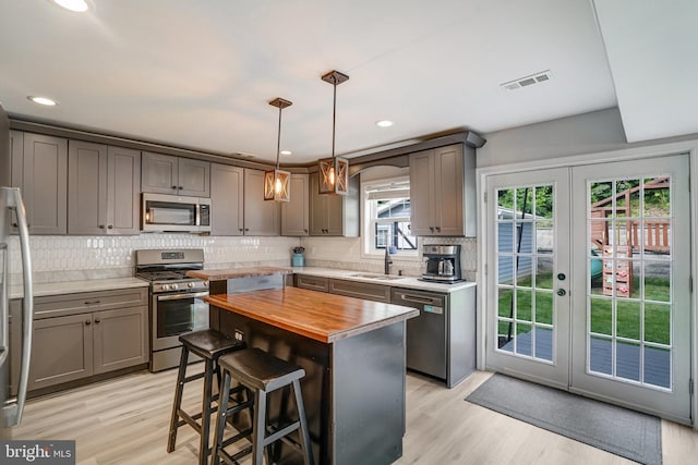 6022 Rixey Dr, Alexandria, VA 22303 - kitchen with stainless steel appliances, wooden counters, gray cabinetry, decorative backsplash, and recessed lighting