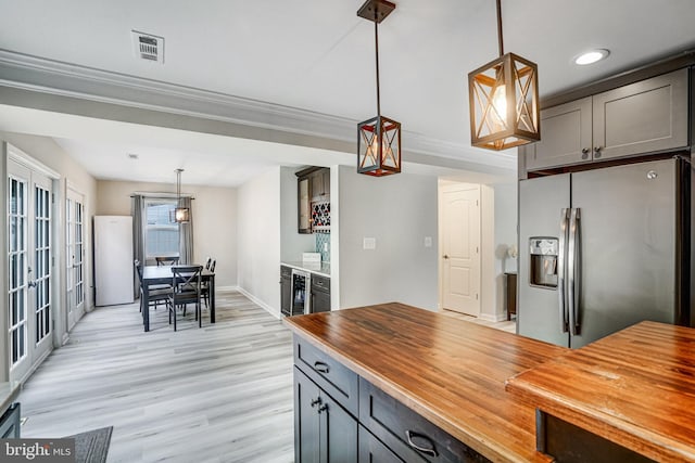 6022 Rixey Dr, Alexandria, VA 22303 - kitchen with stainless steel fridge, wood counters, light wood finished floors, freestanding refrigerator, and pendant lighting