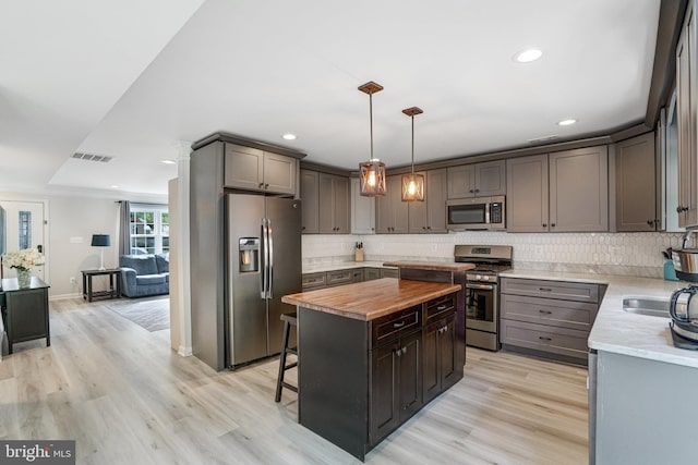 6022 Rixey Dr, Alexandria, VA 22303 - kitchen with stainless steel appliances, butcher block counters, a center island, decorative backsplash, and light wood-type flooring