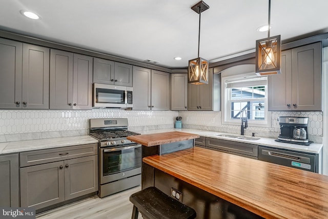 6022 Rixey Dr, Alexandria, VA 22303 - kitchen with stainless steel appliances, gray cabinetry, tasteful backsplash, hanging light fixtures, and recessed lighting