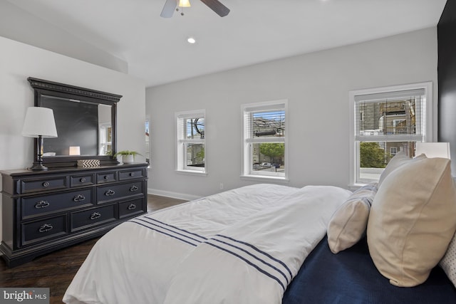 bedroom with dark wood-style floors, baseboards, ceiling fan, and multiple windows