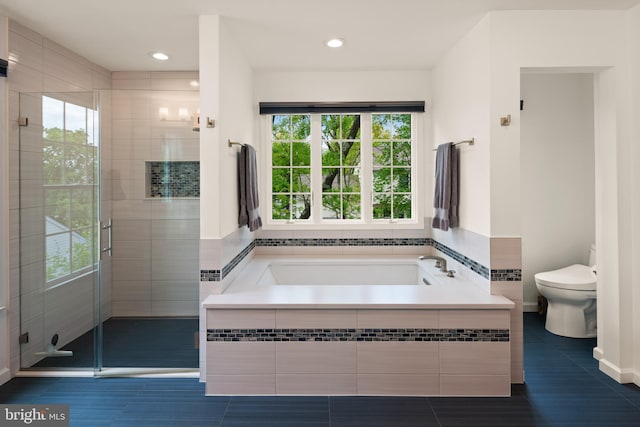 full bath featuring tile patterned floors, plenty of natural light, toilet, and a bath