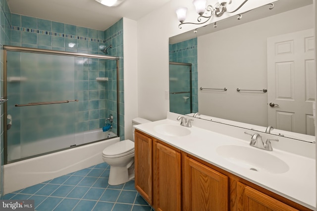 bathroom with toilet, tile patterned floors, a sink, and bath / shower combo with glass door