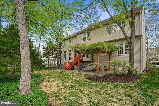 rear view of property featuring a lawn, a patio, a chimney, and stairs