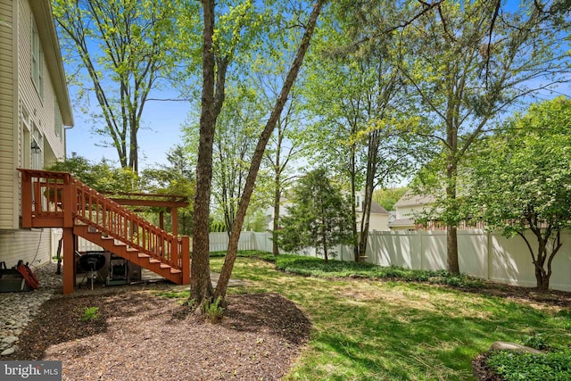 view of yard with fence, a wooden deck, and stairway