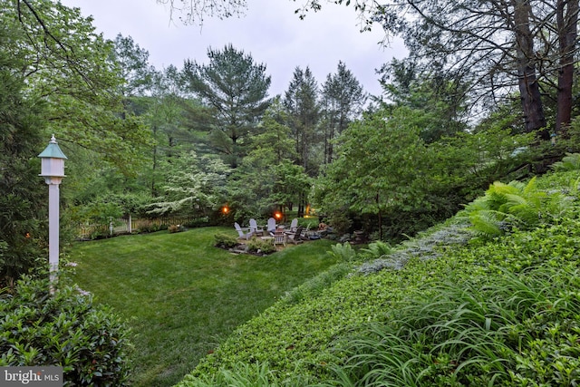 view of green lawn with an outdoor fire pit and a patio