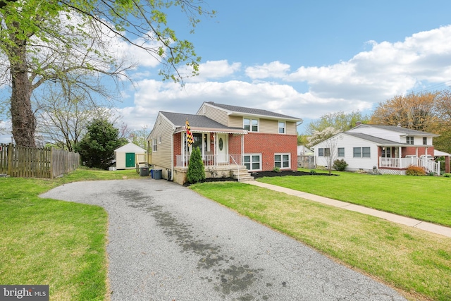 split level home featuring fence, an outbuilding, gravel driveway, brick siding, and a storage unit