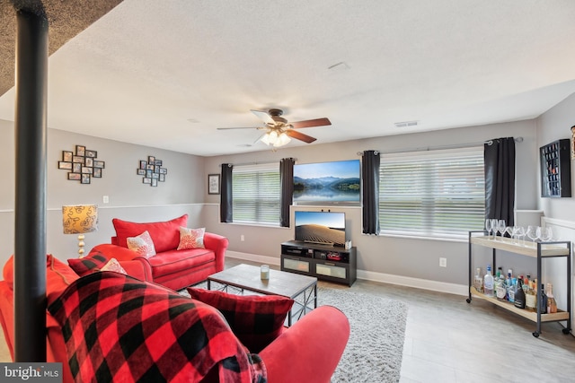 living room with baseboards, a ceiling fan, and visible vents