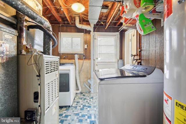 clothes washing area featuring separate washer and dryer, tile patterned floors, laundry area, and gas water heater