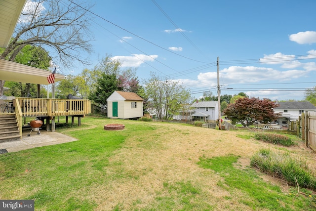view of yard with a storage shed, an outdoor fire pit, fence, an outbuilding, and a wooden deck