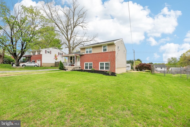 view of front of house with fence, brick siding, and a front yard