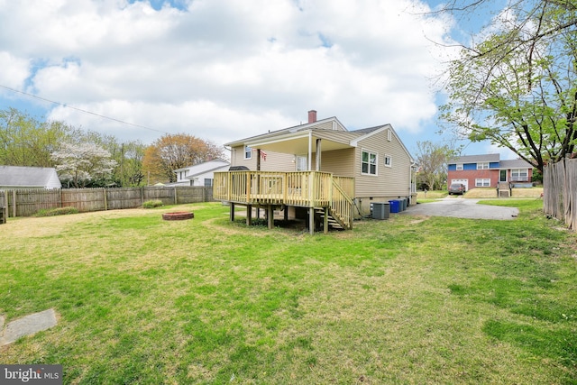 back of house featuring a yard, a fenced backyard, an outdoor fire pit, and a deck