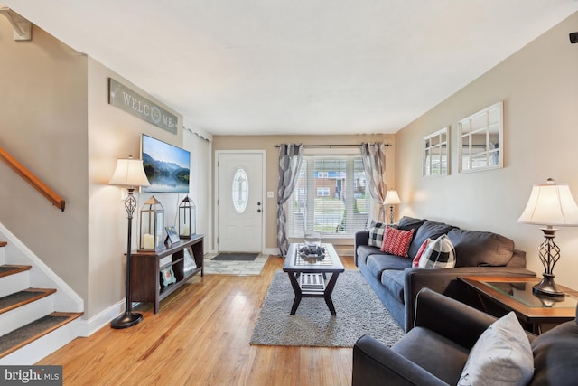 living room with stairway, baseboards, and light wood-style flooring