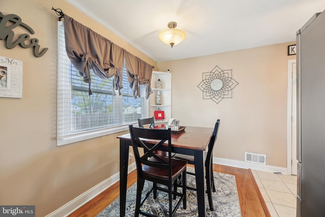 dining space featuring baseboards, light wood-style flooring, and visible vents