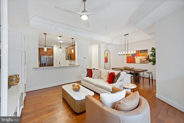 living room with crown molding, baseboards, a tray ceiling, and hardwood / wood-style floors