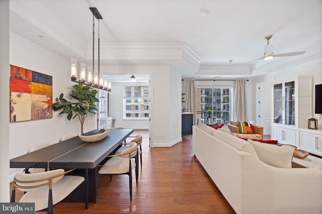 living area featuring crown molding, a ceiling fan, a raised ceiling, and wood finished floors