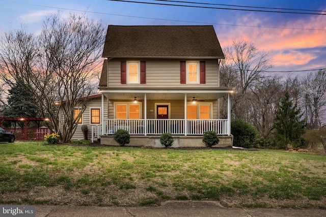 view of front of house featuring a front yard, covered porch, and roof with shingles