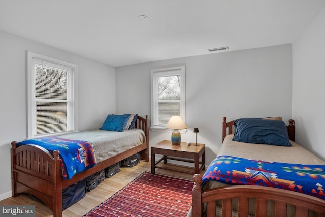 bedroom with wood finished floors, visible vents, and baseboards