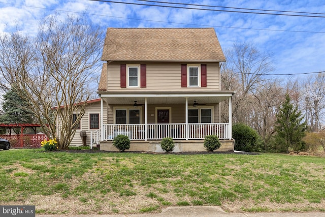 country-style home with a front yard, ceiling fan, covered porch, and roof with shingles