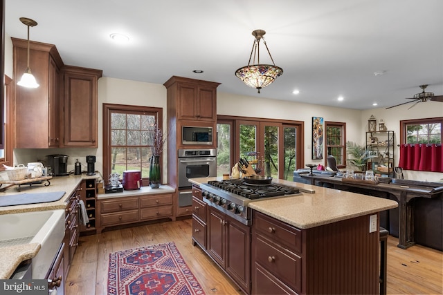 kitchen with recessed lighting, light wood-style floors, appliances with stainless steel finishes, a kitchen island, and a ceiling fan