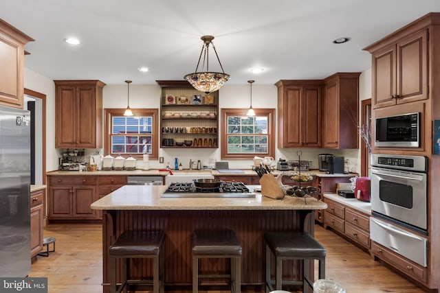 kitchen featuring a warming drawer, a kitchen breakfast bar, appliances with stainless steel finishes, and light wood-type flooring