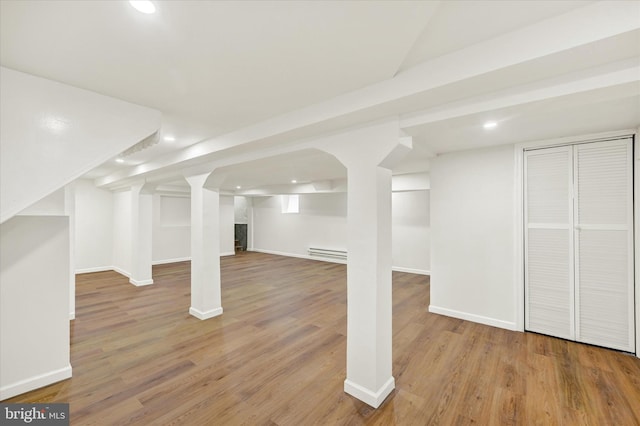 finished below grade area with recessed lighting, a baseboard heating unit, and wood finished floors