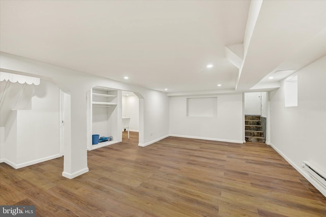 finished below grade area featuring baseboards, baseboard heating, stairway, recessed lighting, and wood finished floors