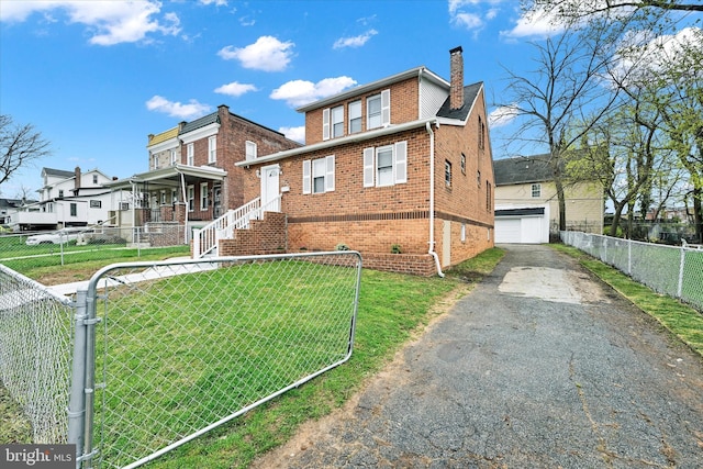 view of front of house with brick siding, a front lawn, an outdoor structure, and fence private yard