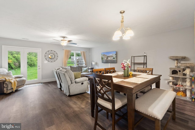 dining room featuring ceiling fan with notable chandelier, dark wood-style flooring, and baseboards