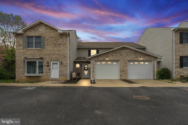traditional-style house with a garage, aphalt driveway, and brick siding