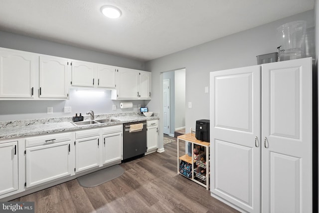 kitchen with dark wood-style flooring, light stone counters, white cabinetry, dishwasher, and a sink
