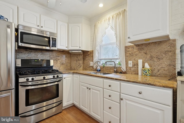 7121 Lawndale Ave, Philadelphia, PA 19111 - kitchen featuring white cabinets, a sink, stainless steel appliances, light wood-style flooring, and light stone counters