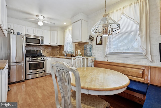 7121 Lawndale Ave, Philadelphia, PA 19111 - kitchen with light wood-type flooring, appliances with stainless steel finishes, decorative backsplash, and white cabinetry