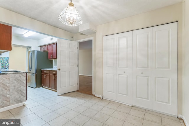 interior space featuring a chandelier, baseboards, freestanding refrigerator, and light tile patterned flooring