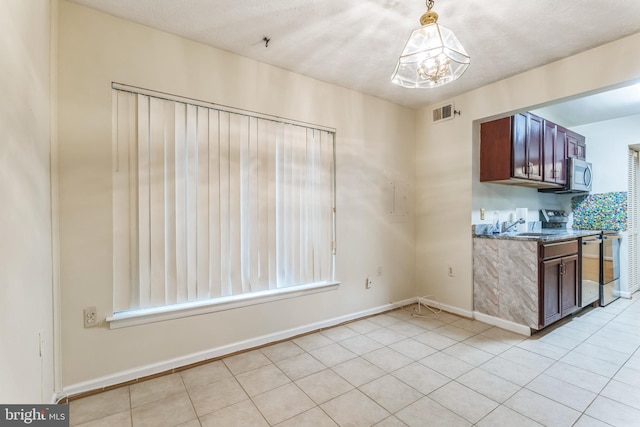 kitchen featuring stainless steel microwave, range, an inviting chandelier, light tile patterned flooring, and visible vents