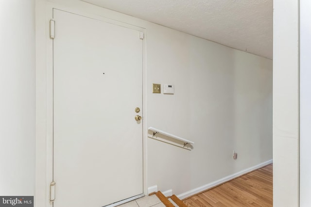 interior space with light wood-style floors, baseboards, and a textured ceiling