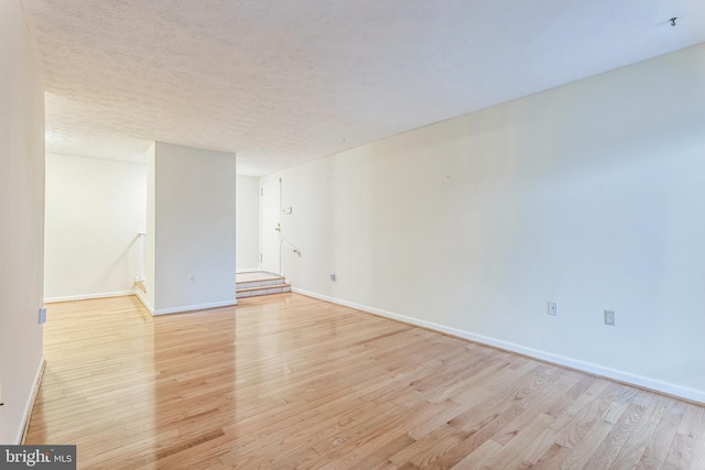empty room featuring baseboards, light wood-style floors, and a textured ceiling