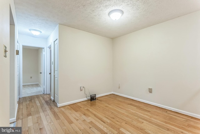 unfurnished room with baseboards, light wood-style floors, and a textured ceiling