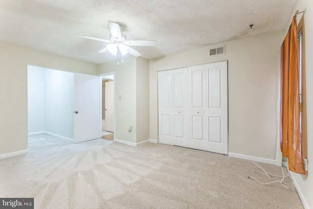 unfurnished bedroom with visible vents, a closet, carpet, and a textured ceiling