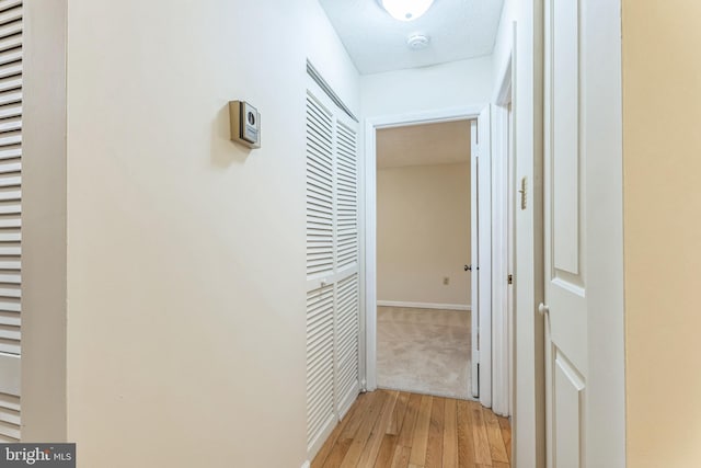 hallway featuring light wood-type flooring and baseboards