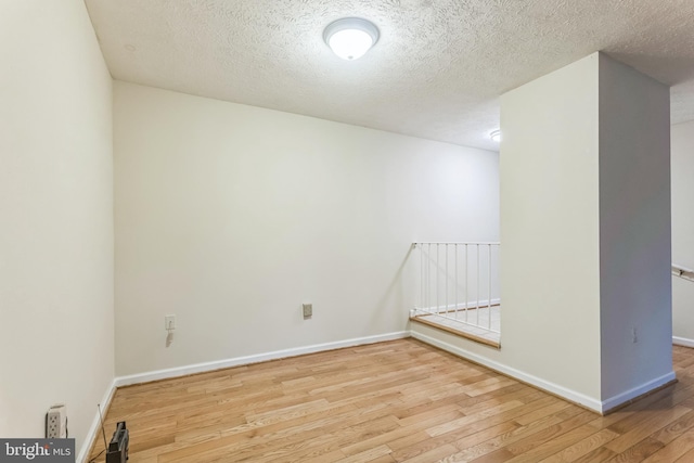 spare room with baseboards, wood finished floors, and a textured ceiling