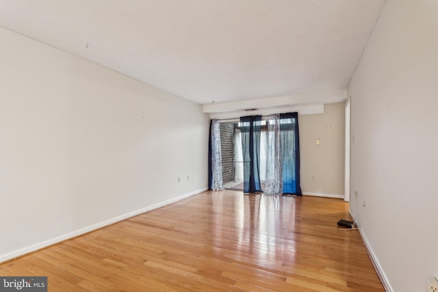 spare room featuring baseboards and light wood-type flooring