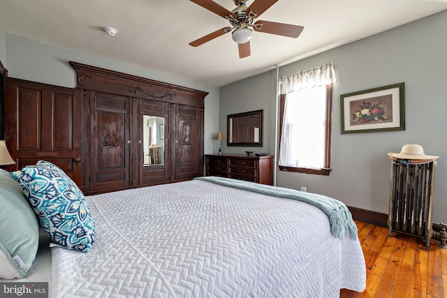 bedroom featuring radiator heating unit, light wood-style floors, baseboards, and a ceiling fan