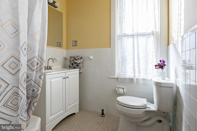 full bath with tile walls, toilet, tile patterned floors, a wainscoted wall, and vanity