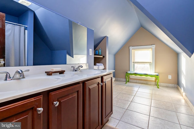 bathroom with vaulted ceiling, tile patterned flooring, plenty of natural light, double vanity, and baseboards