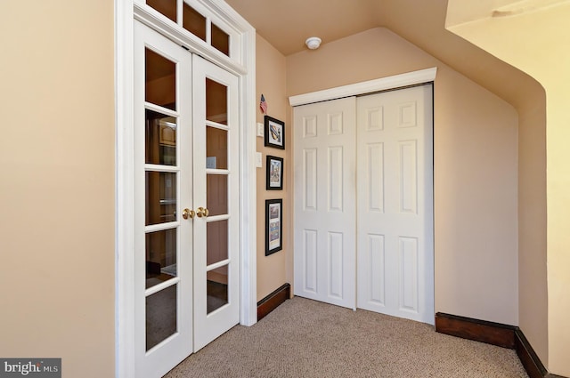 interior space with french doors, carpet flooring, a closet, lofted ceiling, and baseboards