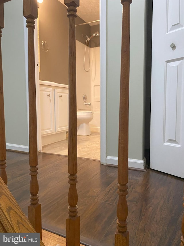 interior space with wood finished floors, shower / tub combination, and baseboards
