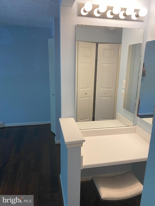 bathroom featuring wood finished floors, a textured ceiling, and baseboards