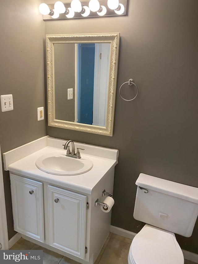 half bath with toilet, vanity, tile patterned flooring, and baseboards