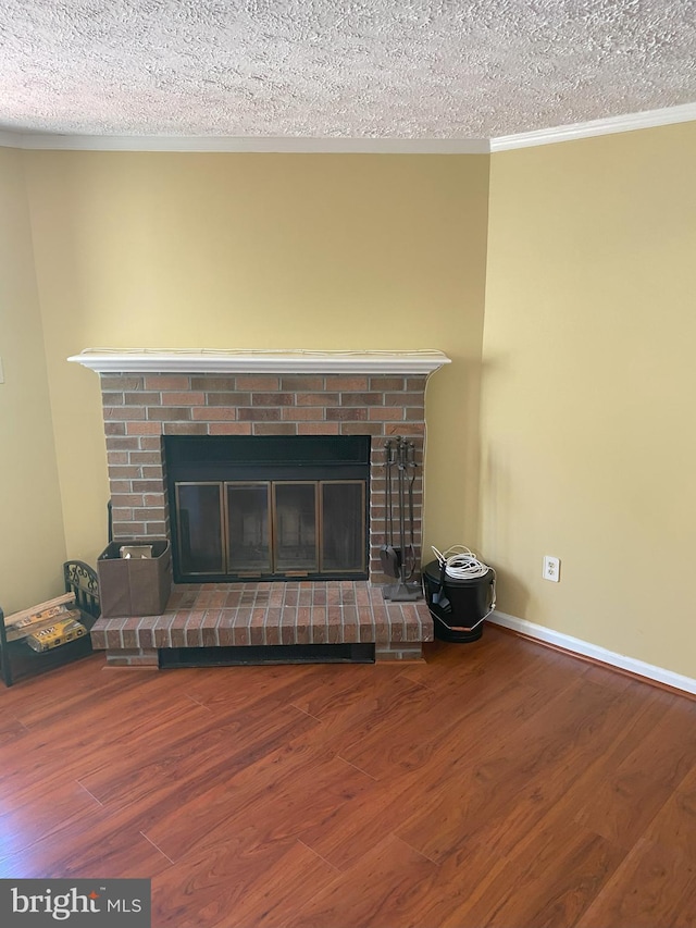 detailed view of a brick fireplace, wood finished floors, a textured ceiling, ornamental molding, and baseboards